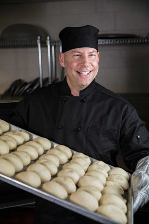 Male employee putting bread into oven